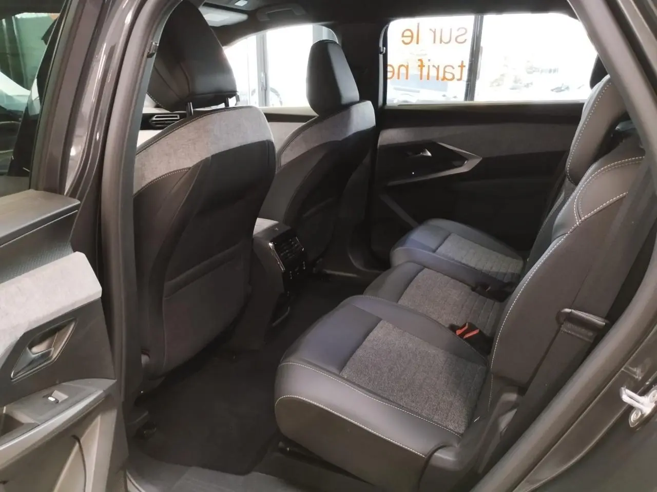 Vue côté droit de l'habitacle arrière du Peugeot 5008 gris titanium, avec sellerie tissu et cuir gris.
