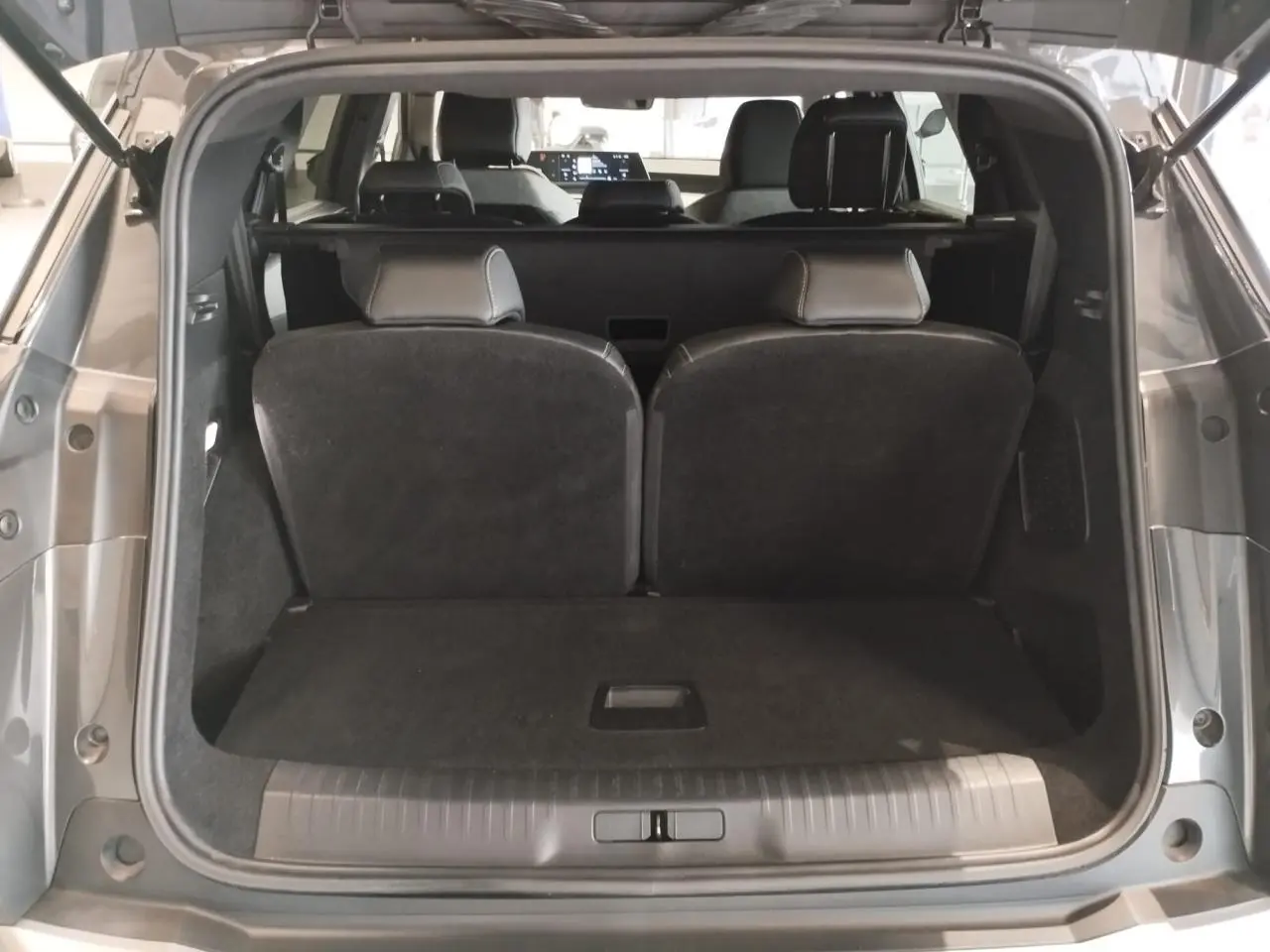 Coffre ouvert vue arrière du Peugeot 5008 gris titanium avec banquette rang 3 relevée et intérieur sombre.