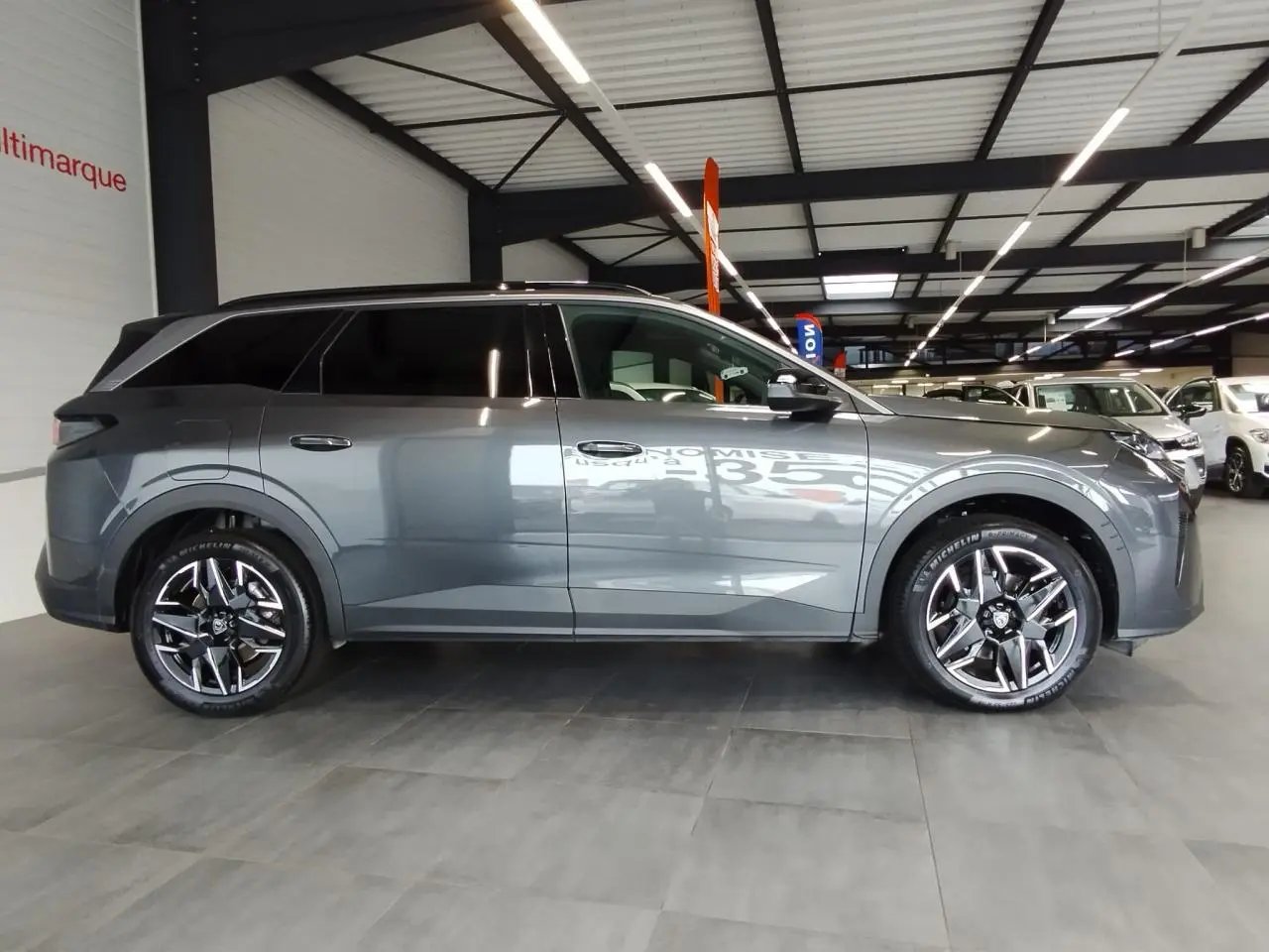 Peugeot 5008 gris titanium vue de profil côté gauche en intérieur avec jantes alliage 19 pouces.