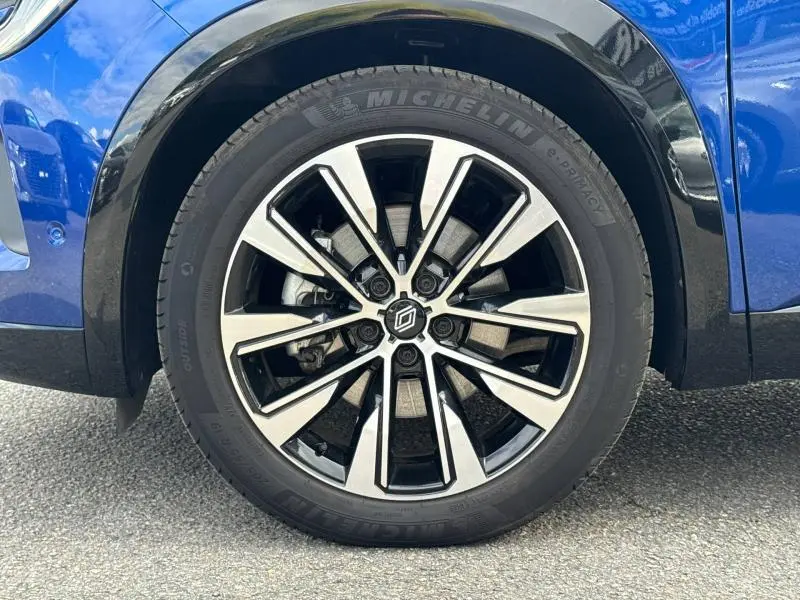 Gros plan sur la roue avant gauche du Renault Austral 2025 bleu Outremer avec jante alliage noire et argentée.