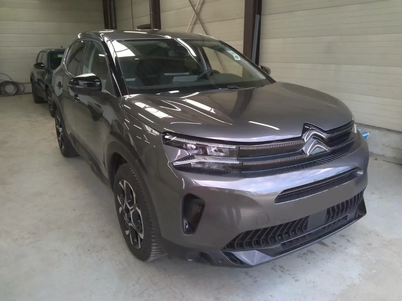 Citroën C5 Aircross 2025 gris platinium en 3/4 avant droit, avec calandre distinctive et phares LED fins.