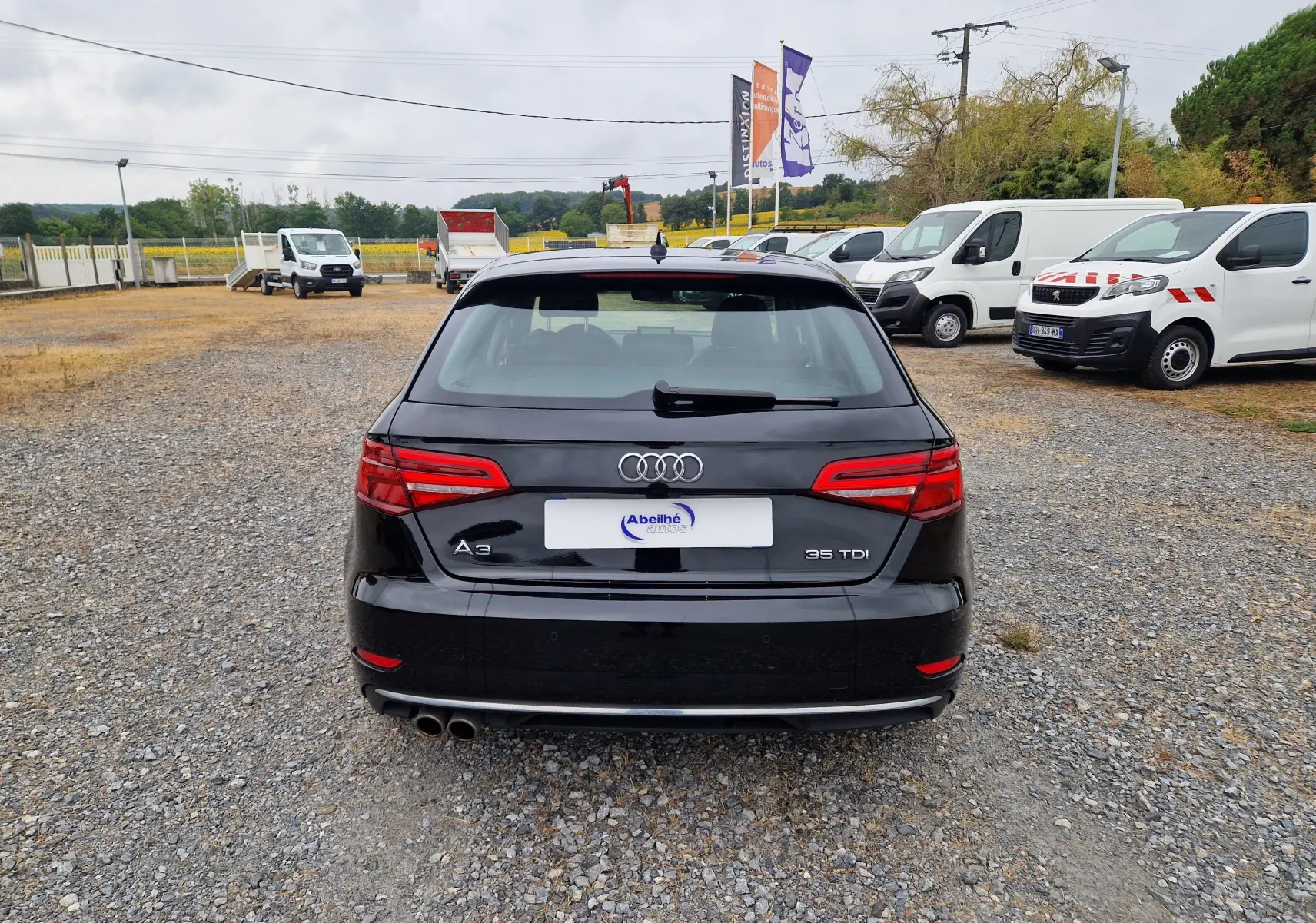 Vue arrière d’une Audi A3 Sportback noire 35 TDI 2019, avec double sortie d’échappement et feux arrière allumés.