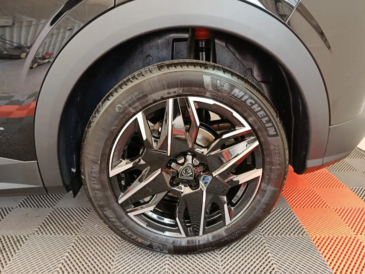 Gros plan sur la roue avant droite noire d’un Peugeot 3008 1.2 Hybrid 145 GT avec jante alliage au design moderne.