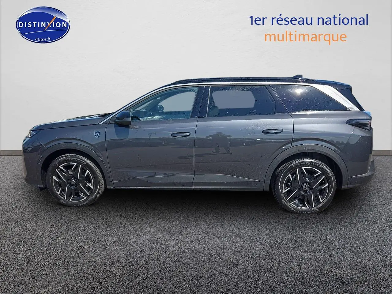 Profil latéral droit du Peugeot 5008 Hybrid 145 GT gris titane avec jantes alliage et vitres arrière surteintées.