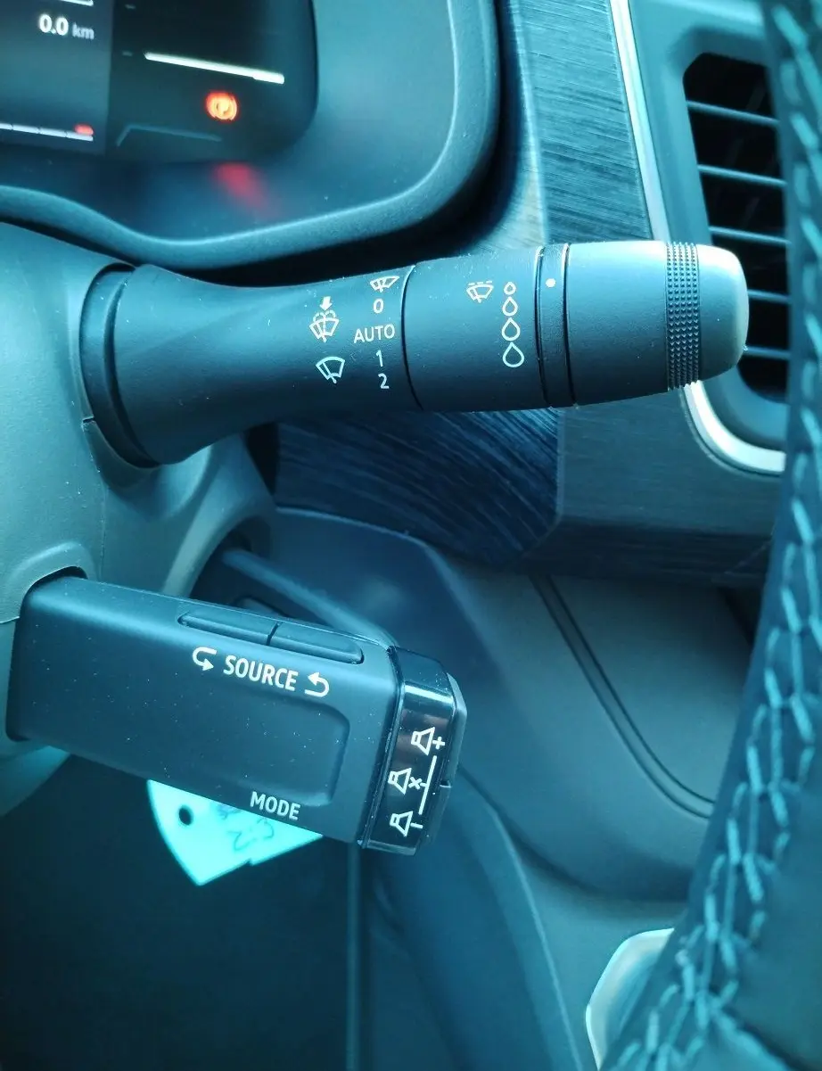 Gros plan sur les commandes de volant du Nissan Primastar 2025, avec levier d'essuie-glace et commande audio noire.