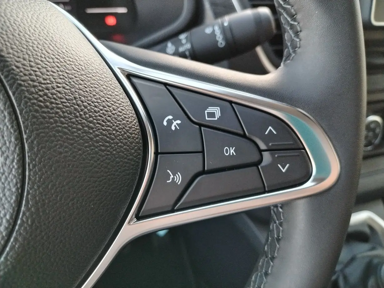 Gros plan sur les commandes multifonctions au volant en cuir noir du Nissan Primastar blanc 2025.