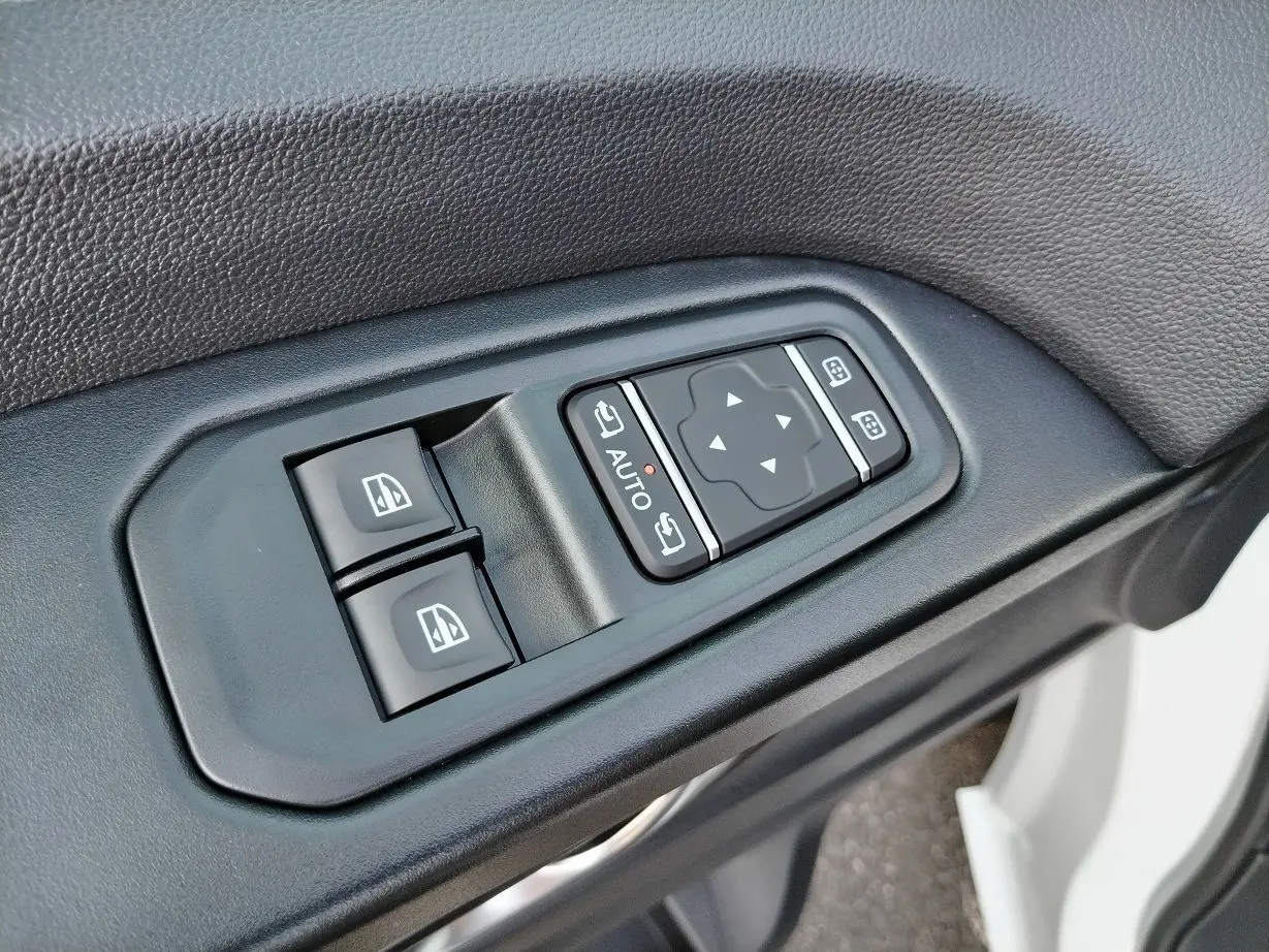 Gros plan sur les commandes de lève-vitres et rétroviseurs côté conducteur d'un Nissan Primastar blanc 2025.