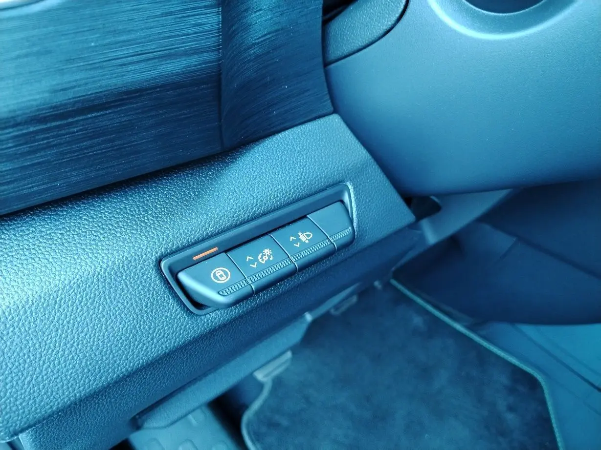 Gros plan sur les commandes de réglage d'éclairage et verrouillage côté gauche du tableau de bord noir du Nissan Primastar blanc 2025.