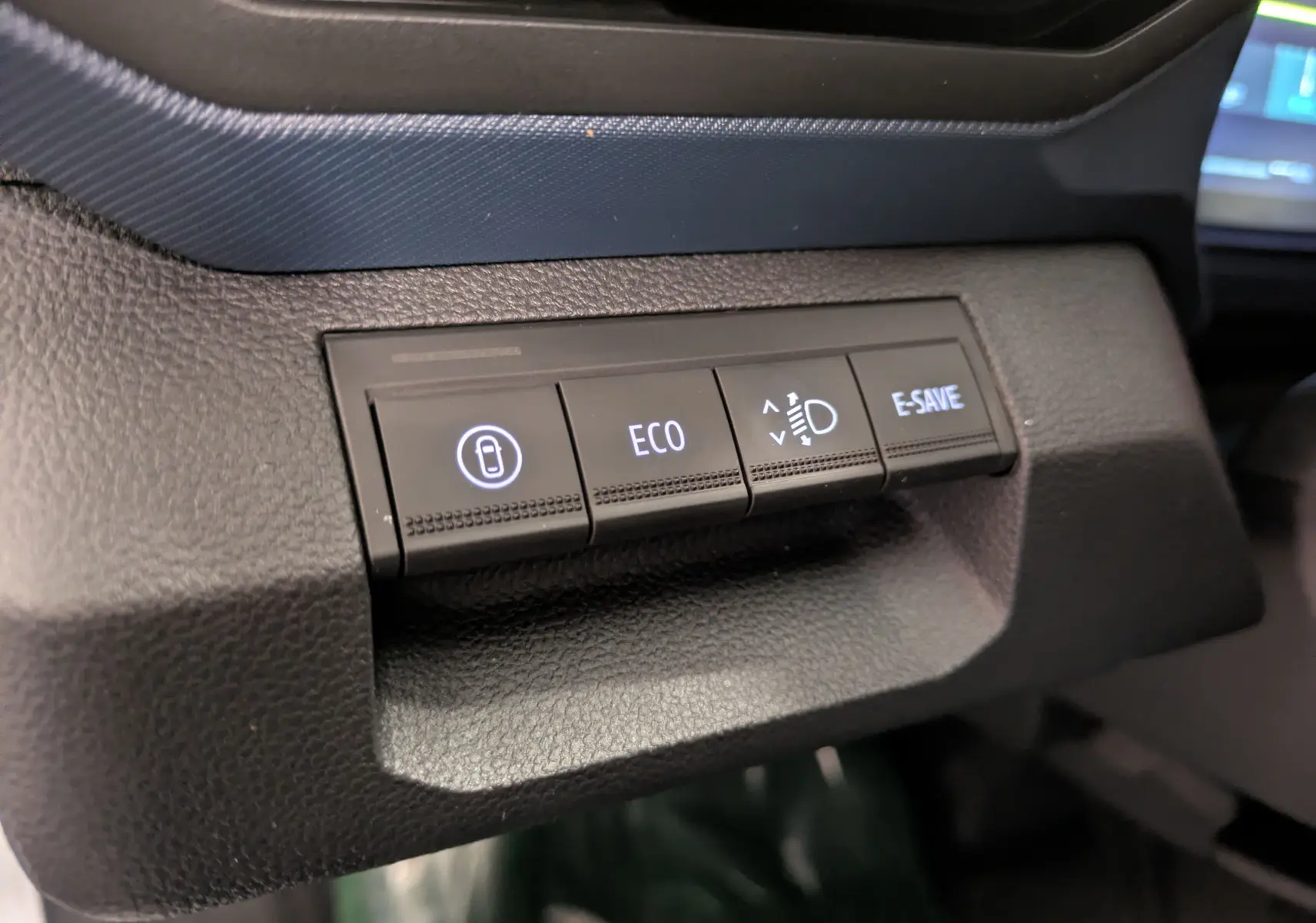 Gros plan sur les boutons de commande du tableau de bord du Dacia Duster Hybrid 140 Journey 2025, avec éclairage blanc.