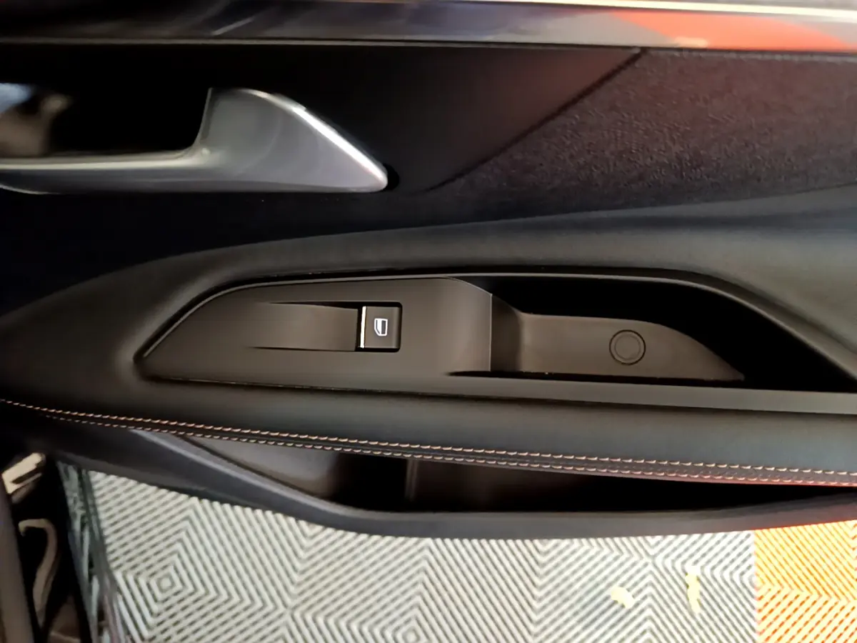 Gros plan sur la poignée intérieure côté gauche de porte noire avec surpiqûres orange du Peugeot 3008 GT 2023.
