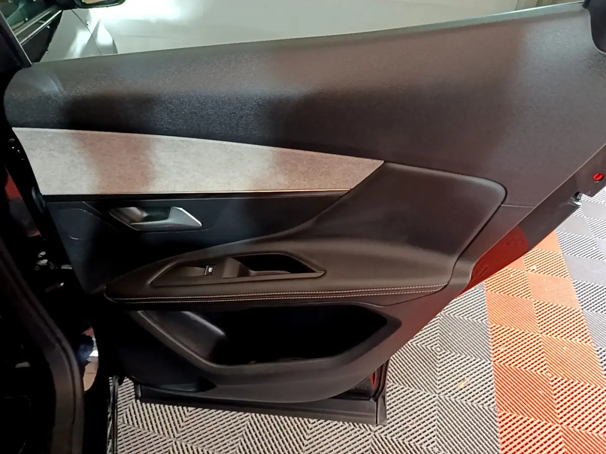 Vue intérieure côté gauche de la porte avant noire du Peugeot 3008 2023 avec garniture tissu et commandes électriques.