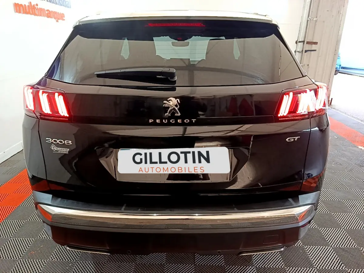 Vue arrière d’un Peugeot 3008 GT noir avec feux LED allumés et logo Peugeot visible sur le hayon.