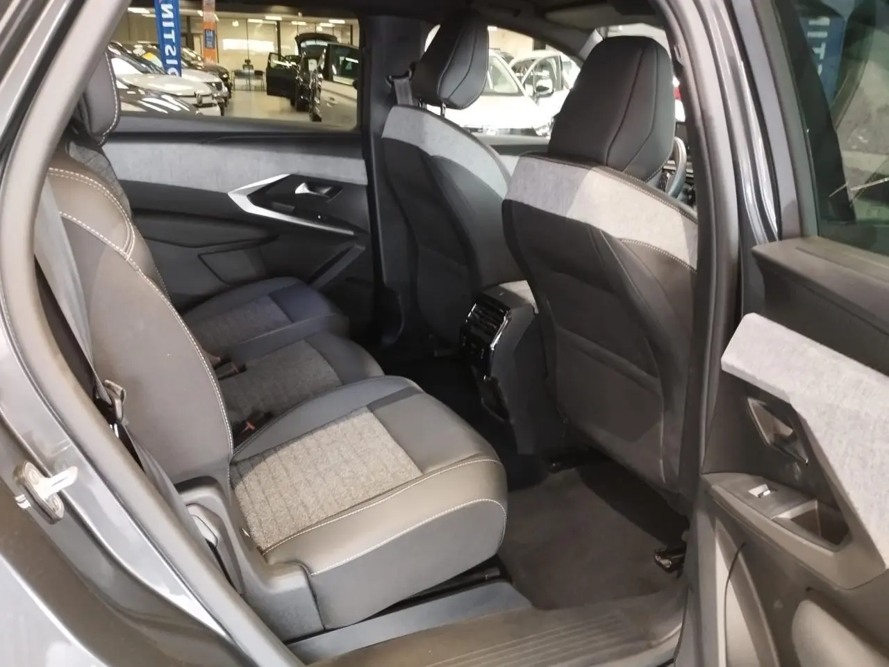 Vue intérieure côté gauche des sièges arrière du Peugeot 5008 gris titanium, avec sellerie tissu et cuir bicolore.