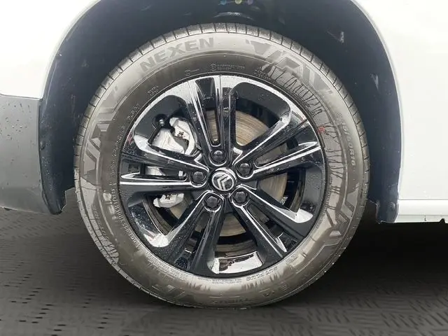 Gros plan sur la roue avant droite noire brillante du Citroën Berlingo blanc, mettant en valeur la jante et le pneu Nexen.