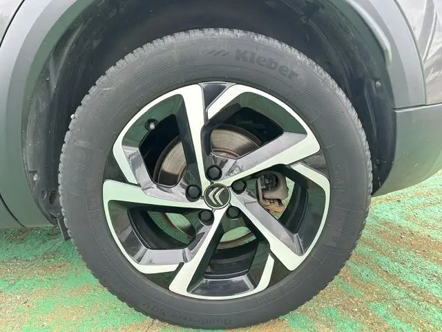 Gros plan sur la roue avant gauche d’un Citroën C5 Aircross marron, jante alliage noire et argentée avec logo Citroën central.