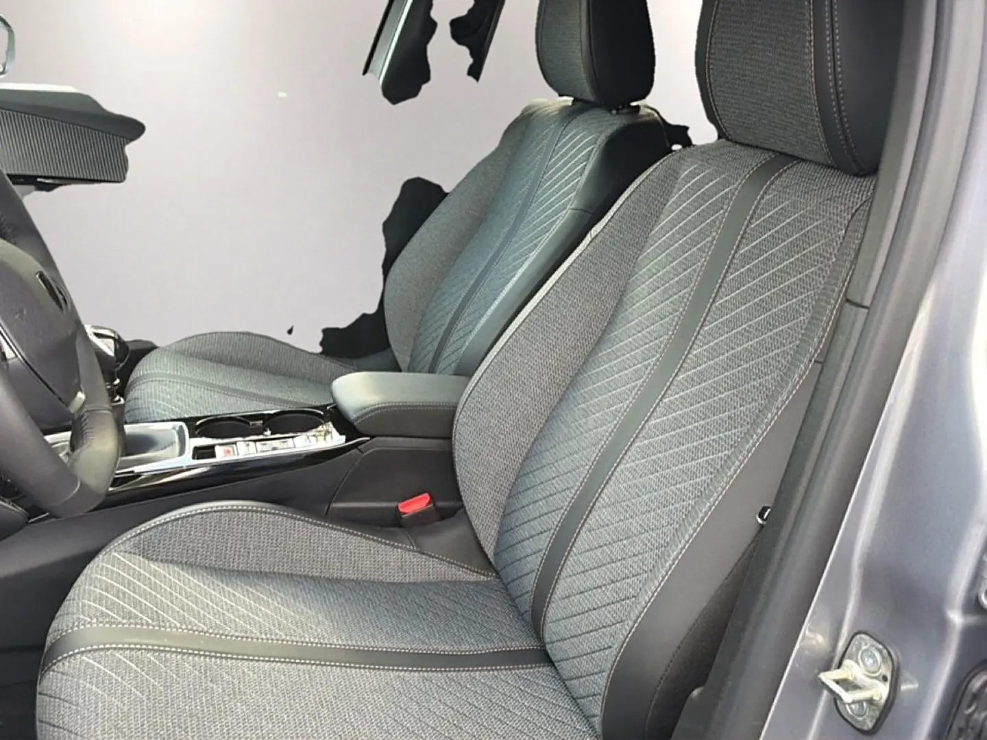 Vue intérieure côté conducteur montrant les sièges en tissu gris embossé du Peugeot 2008 1.2 100 Allure gris Artense.