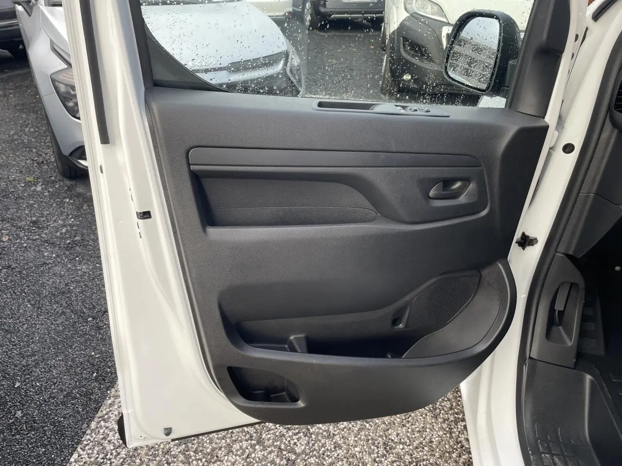 Porte avant gauche ouverte d'un Opel Vivaro blanc 2024, panneau intérieur noir avec haut-parleur intégré.