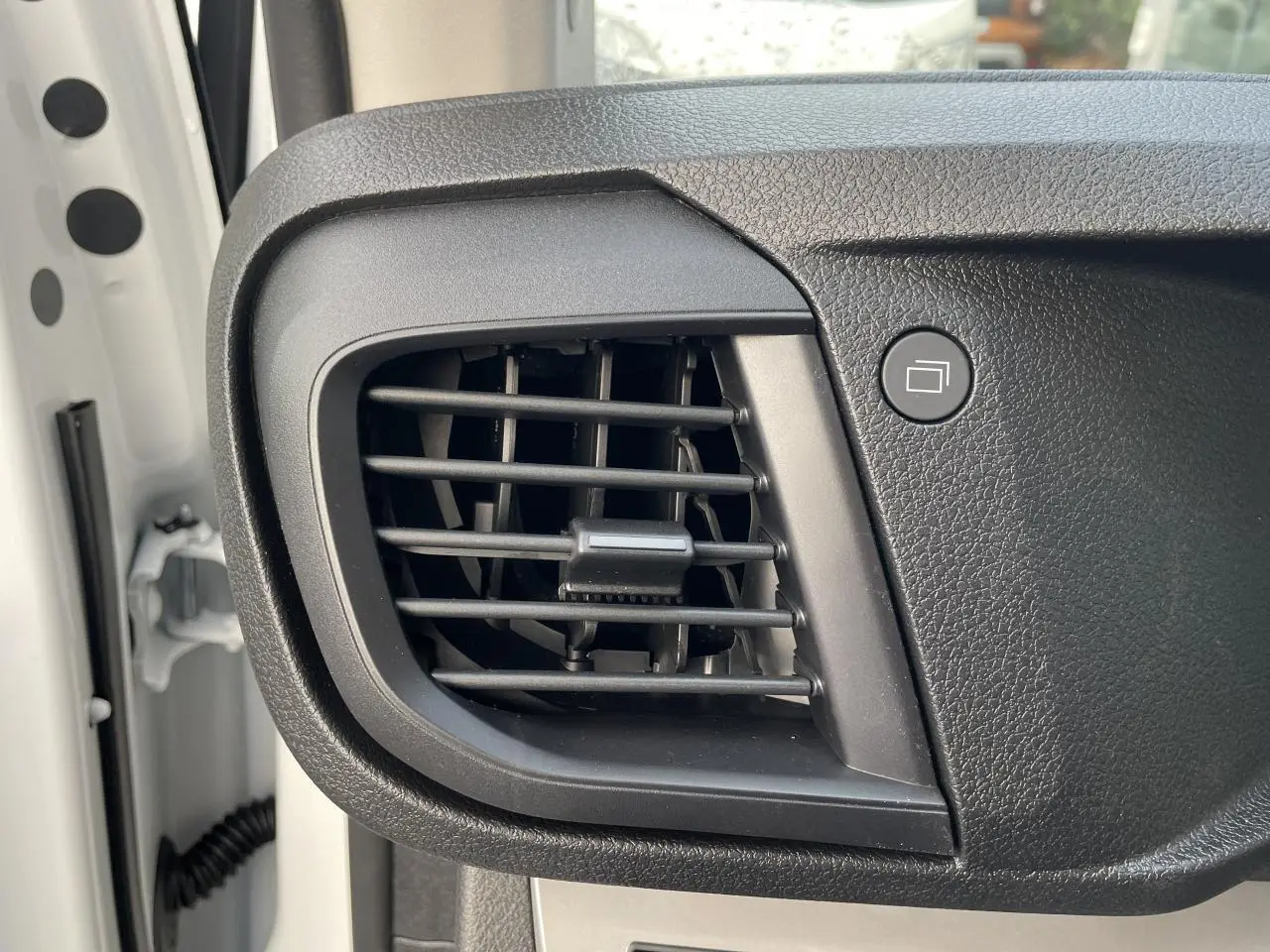 Gros plan sur la grille d'aération noire du tableau de bord côté gauche d'un Opel Vivaro blanc 2024.