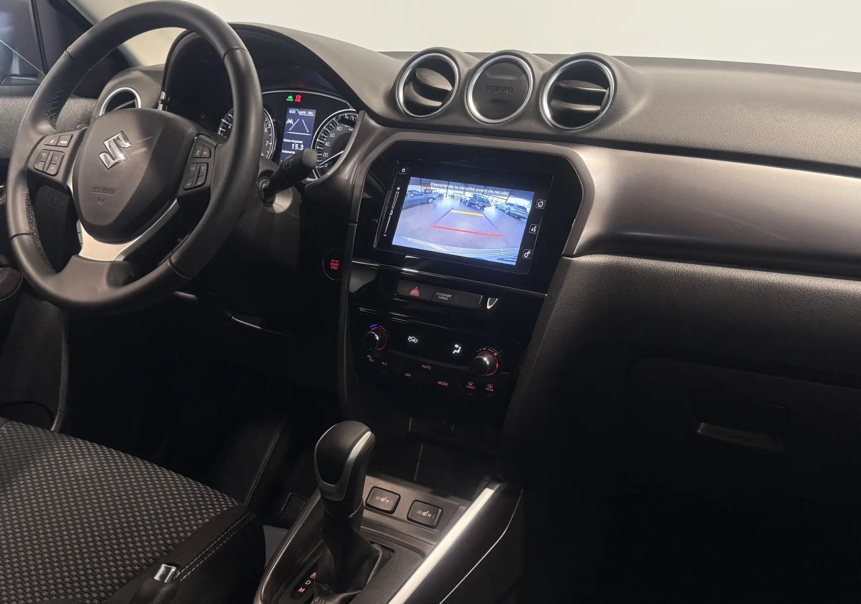 Intérieur du Suzuki Vitara 2023 vu côté conducteur, avec tableau de bord noir et écran multimédia affichant la caméra de recul.