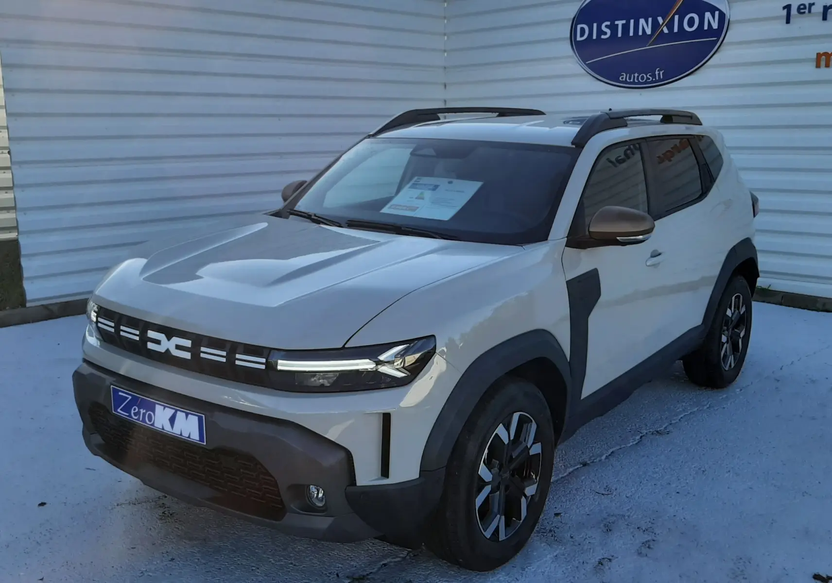 Vue 3/4 avant droite du Dacia Duster 1.6 Hybrid 140ch Extreme couleur Sandstone avec jantes biton et barres de toit noires.