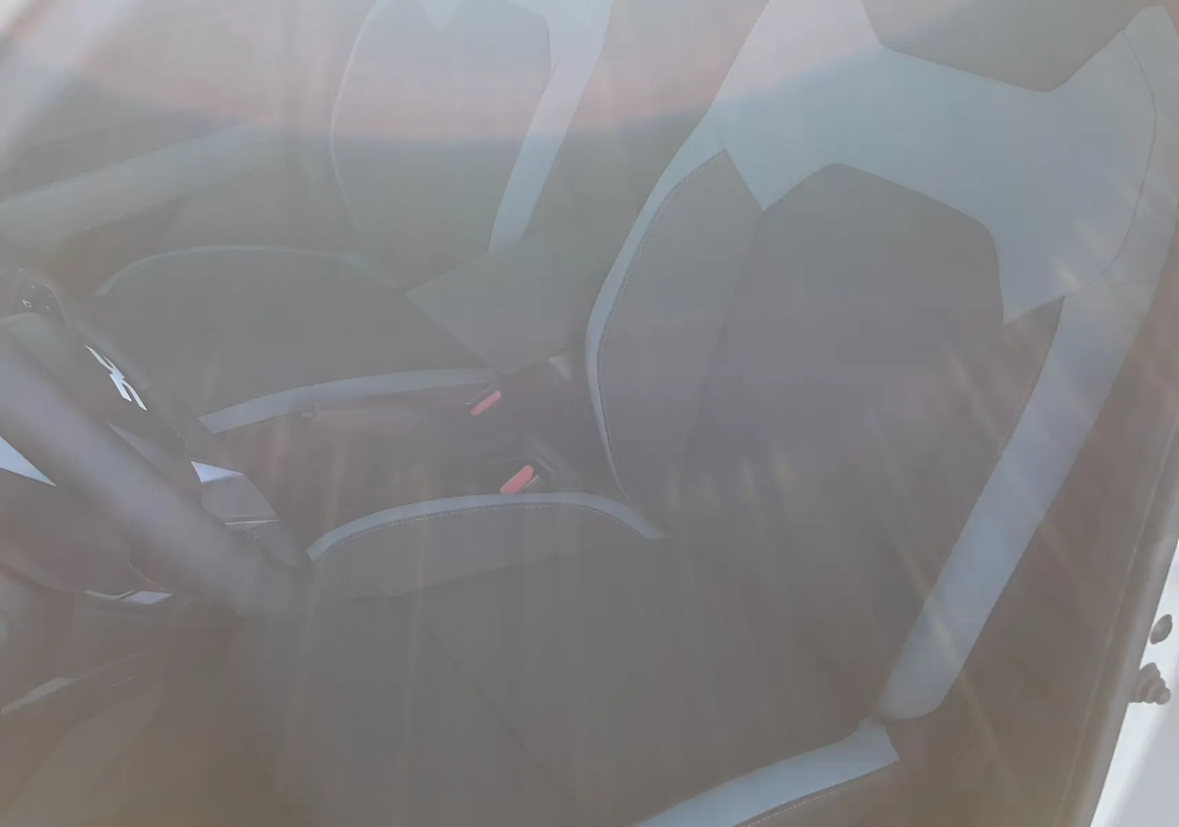 Vue intérieure côté conducteur du Dacia Duster 2025, sièges tissu gris clair et foncé avec détails contrastants.