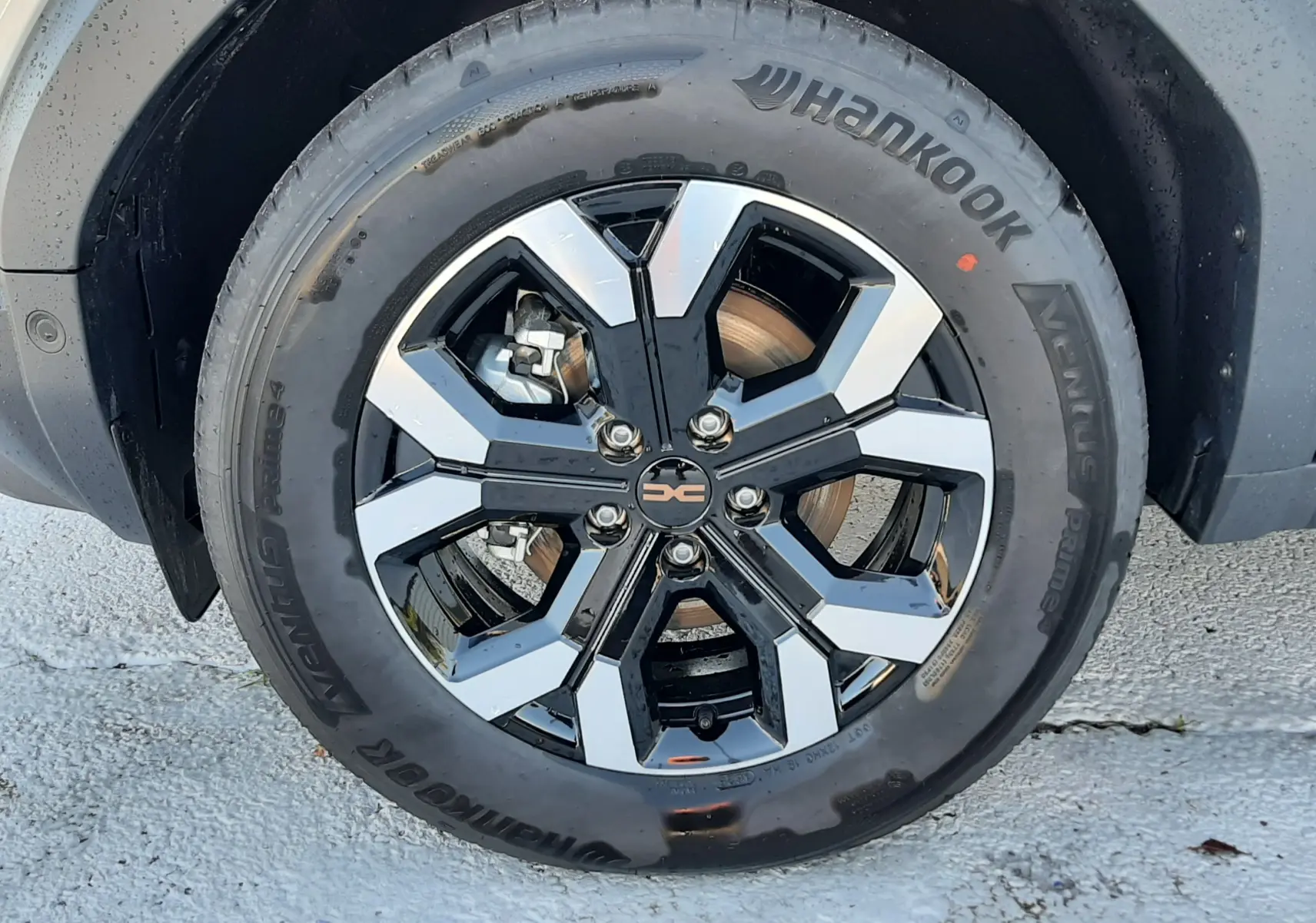 Gros plan sur la roue avant droite du Dacia Duster 1.6 Hybrid 140ch Extreme en couleur Sandstone, jante alliage noire et argent.