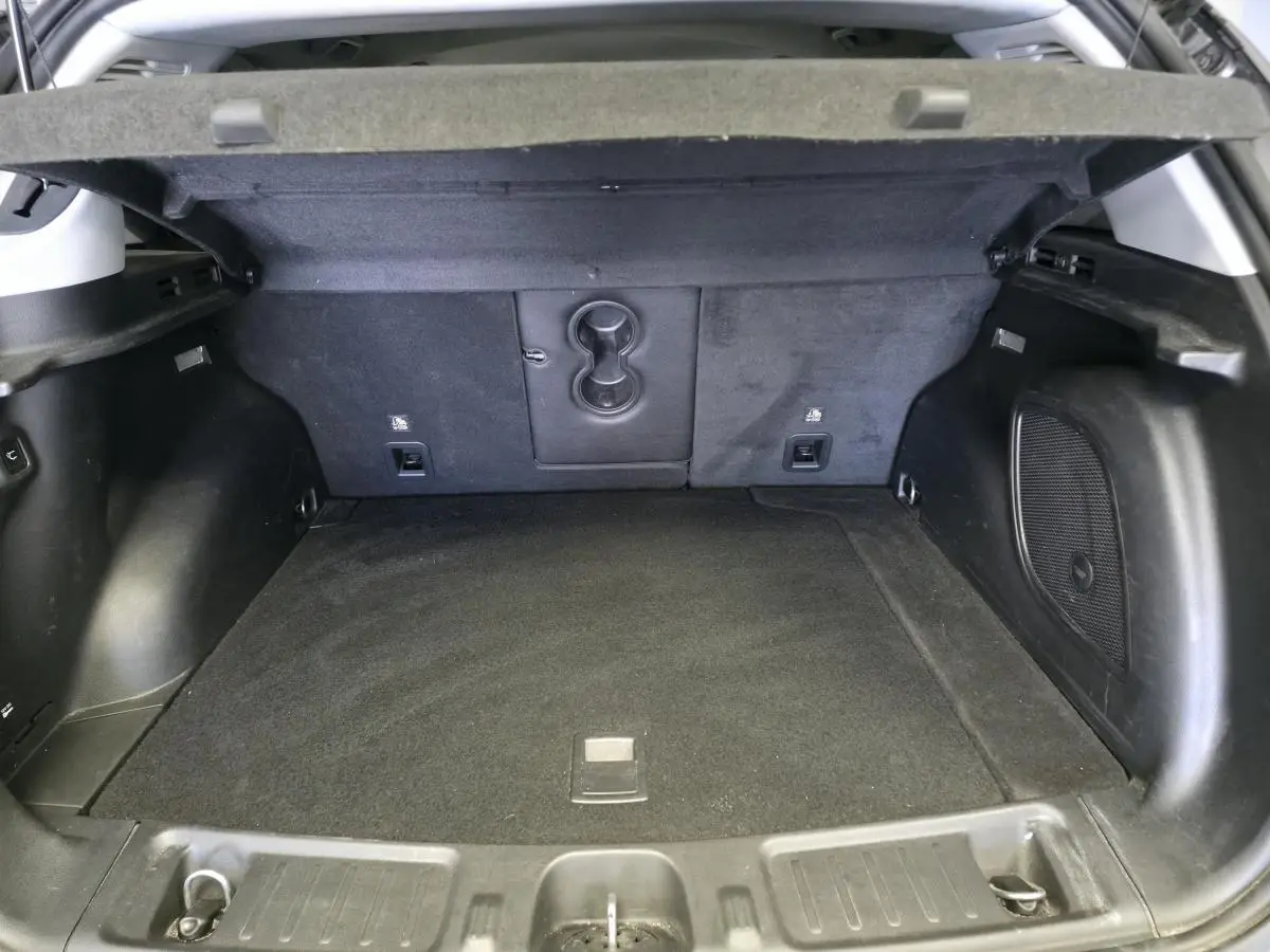 Coffre ouvert vu de l'arrière du Jeep Compass gris foncé, montrant l'espace de chargement et les finitions intérieures noires.