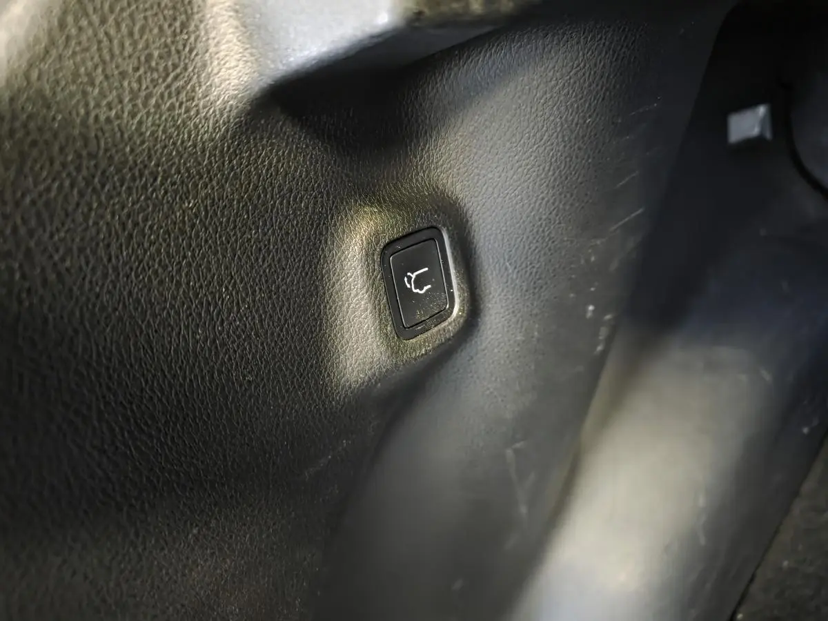 Bouton noir d'ouverture électrique du hayon sur panneau intérieur d'une Jeep Compass gris foncé