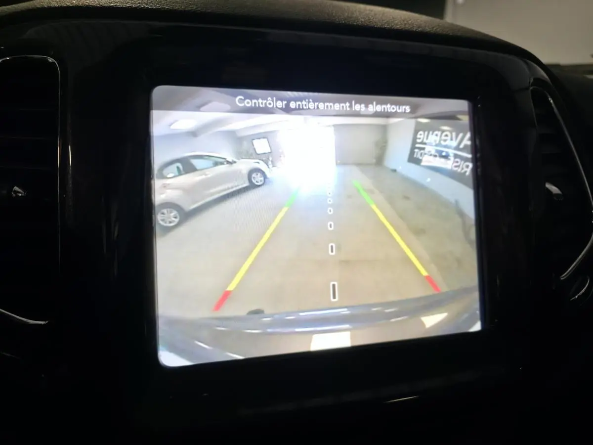 Écran de caméra de recul affichant l'arrière du Jeep Compass gris foncé dans un garage lumineux.