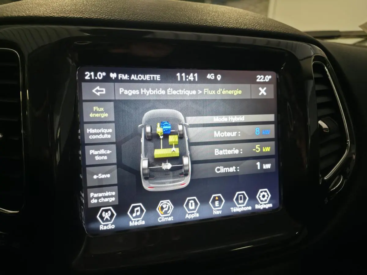 Écran tactile du tableau de bord du Jeep Compass affichant le flux d'énergie hybride en intérieur noir brillant.