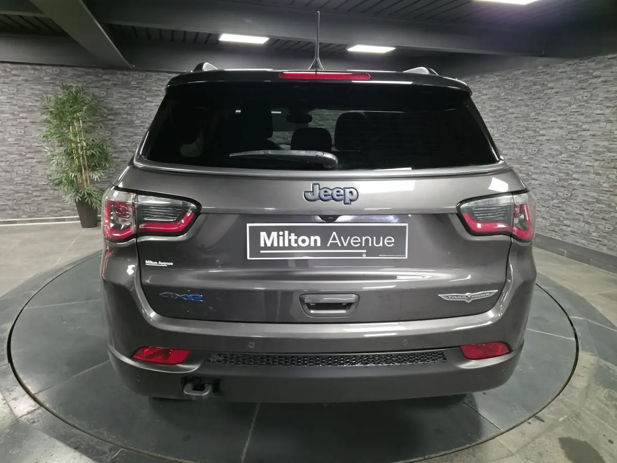 Vue arrière d'un Jeep Compass gris foncé avec hayon électrique et badges Trailhawk et 4xe visibles.