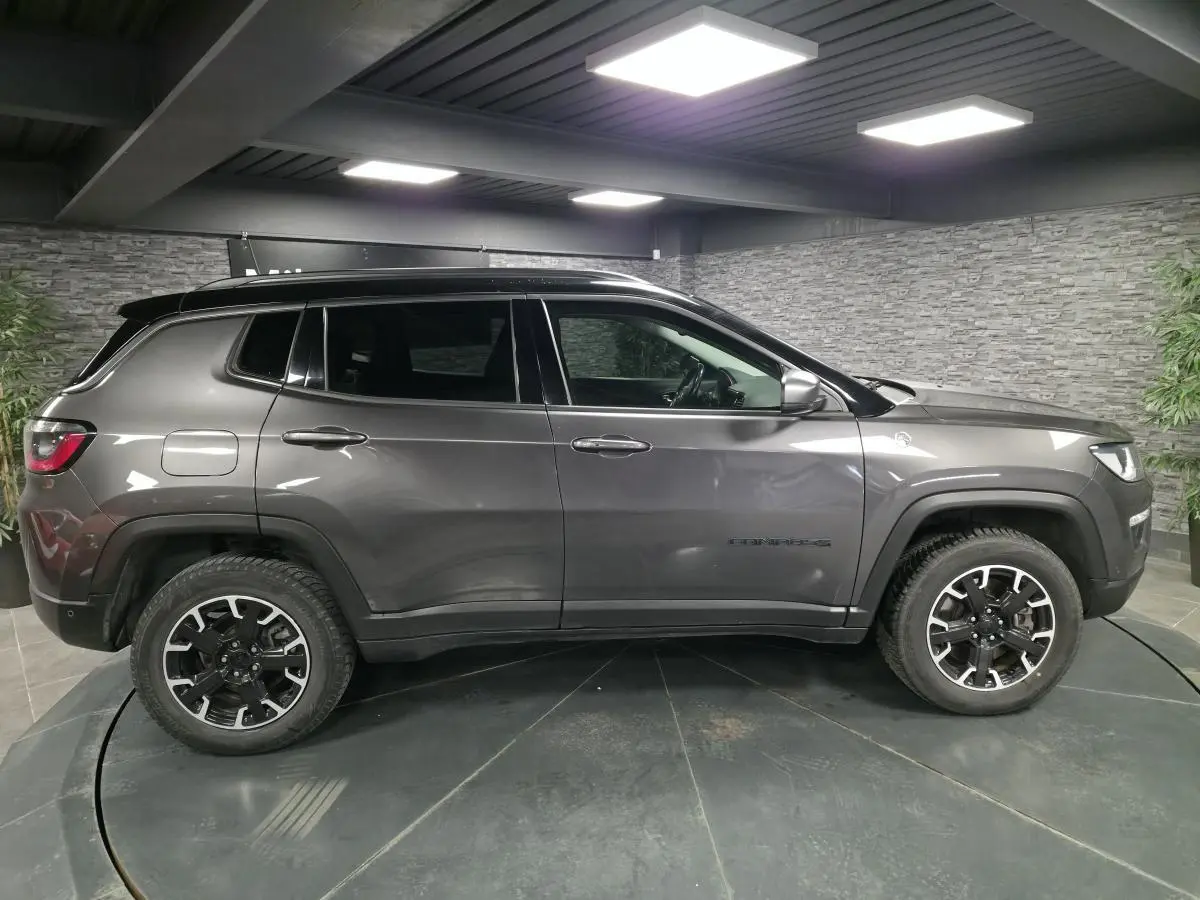 Jeep Compass gris foncé vu de profil côté gauche, avec jantes alliage noires et toit noir contrasté.