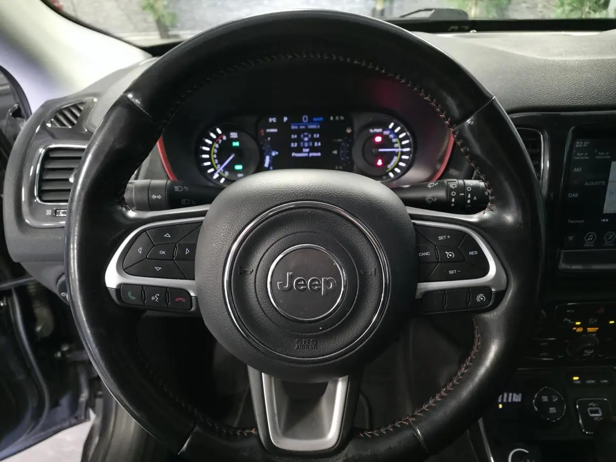 Volant cuir noir Jeep en gros plan avec commandes intégrées, tableau de bord numérique et écran tactile visible à droite