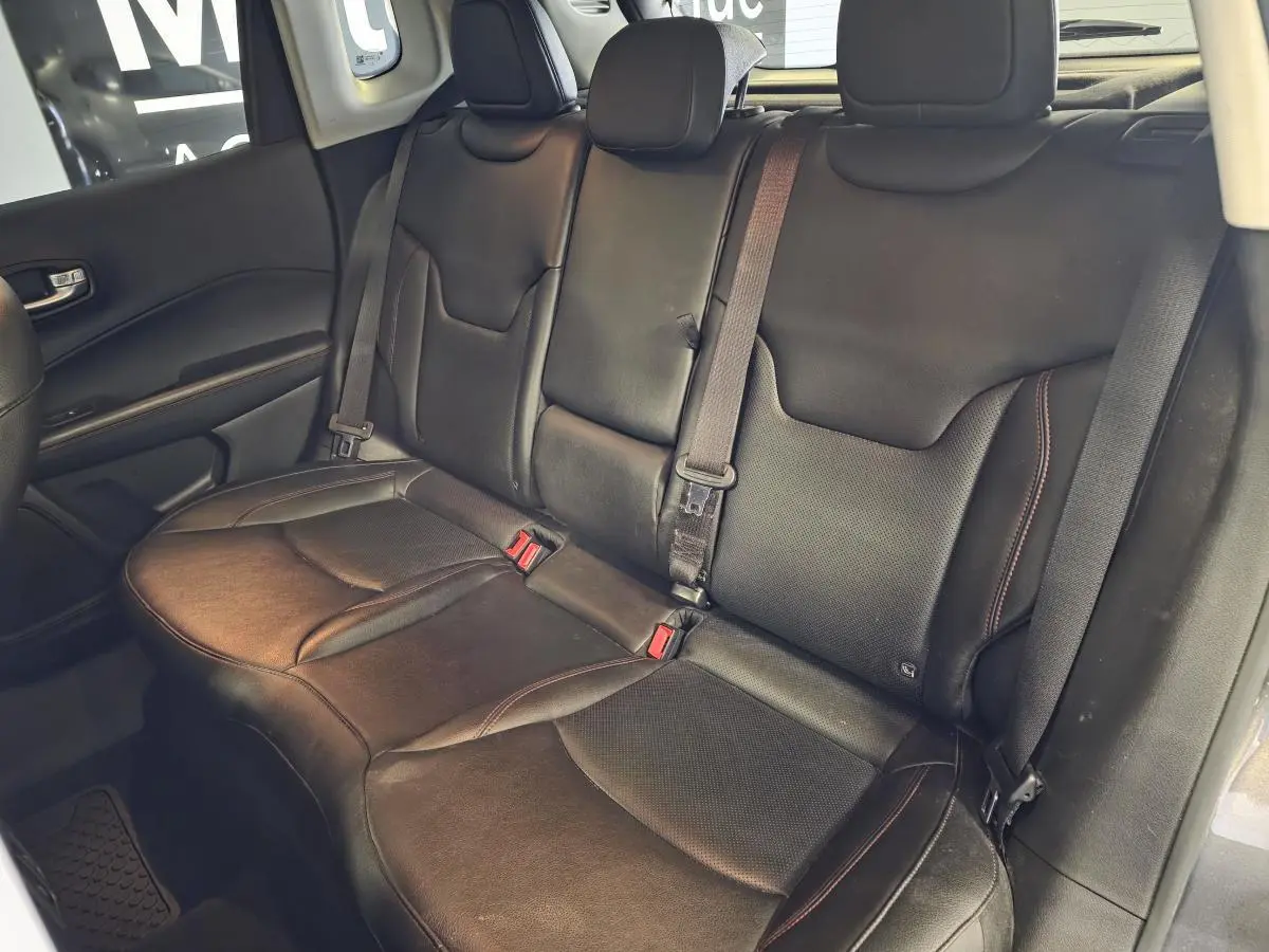 Banquette arrière en cuir noir du Jeep Compass 2020, vue latérale gauche avec ceintures de sécurité visibles.