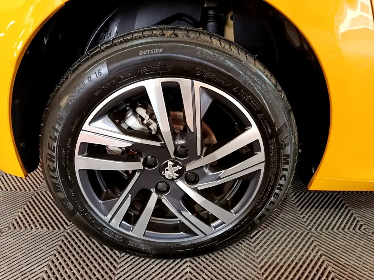 Gros plan sur la roue avant droite de la Peugeot 208 jaune 2023, avec jante alliage et pneu Michelin visible.