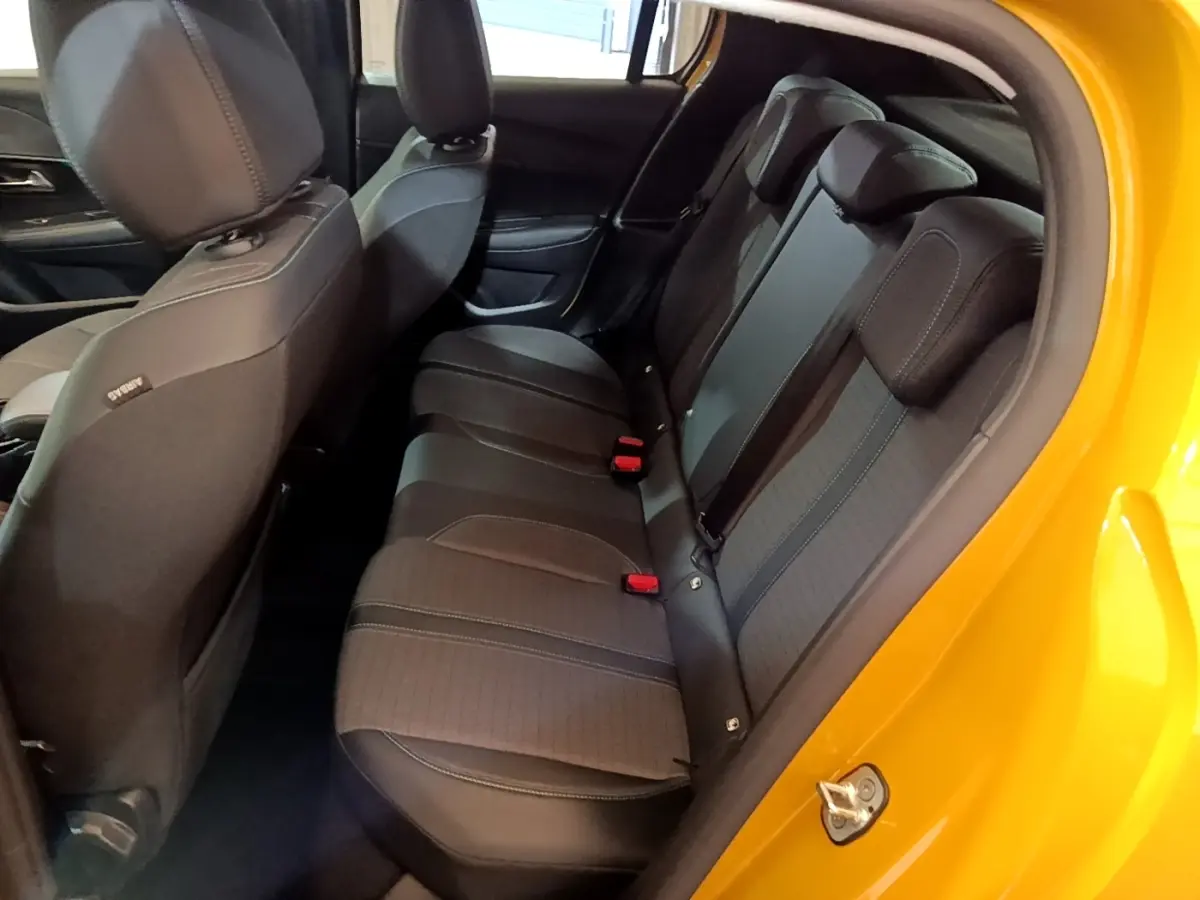 Vue intérieure côté droit des sièges arrière noirs d'une Peugeot 208 jaune 2023 avec portière ouverte.