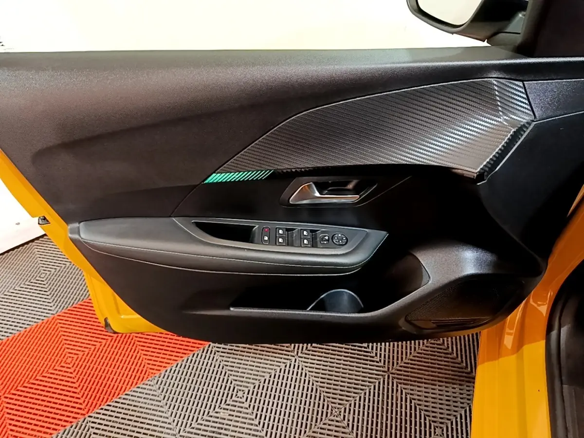 Vue rapprochée de la porte avant gauche jaune de la Peugeot 208 2023 avec garniture noire et inserts effet carbone.