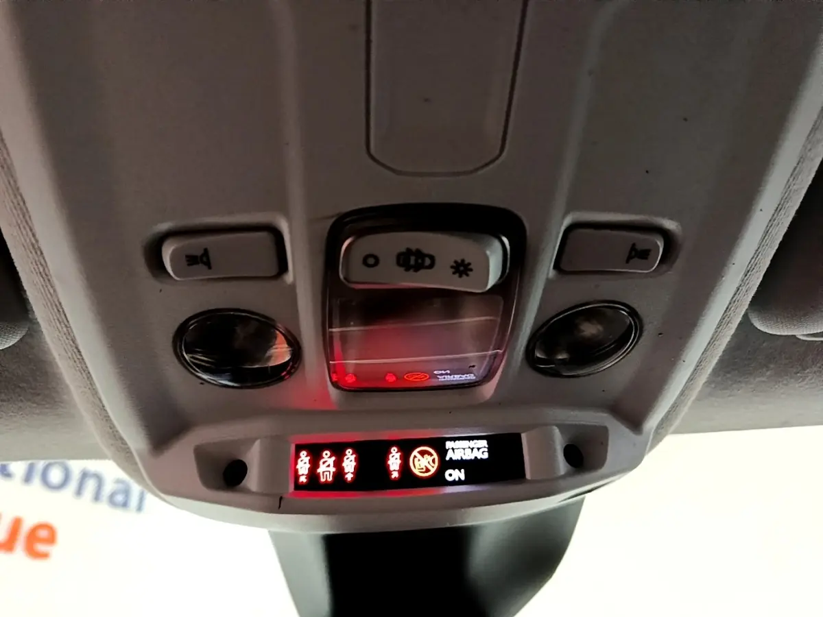 Vue en gros plan du plafonnier intérieur de la Peugeot 208 jaune, avec voyants de ceinture et airbag passager allumés.