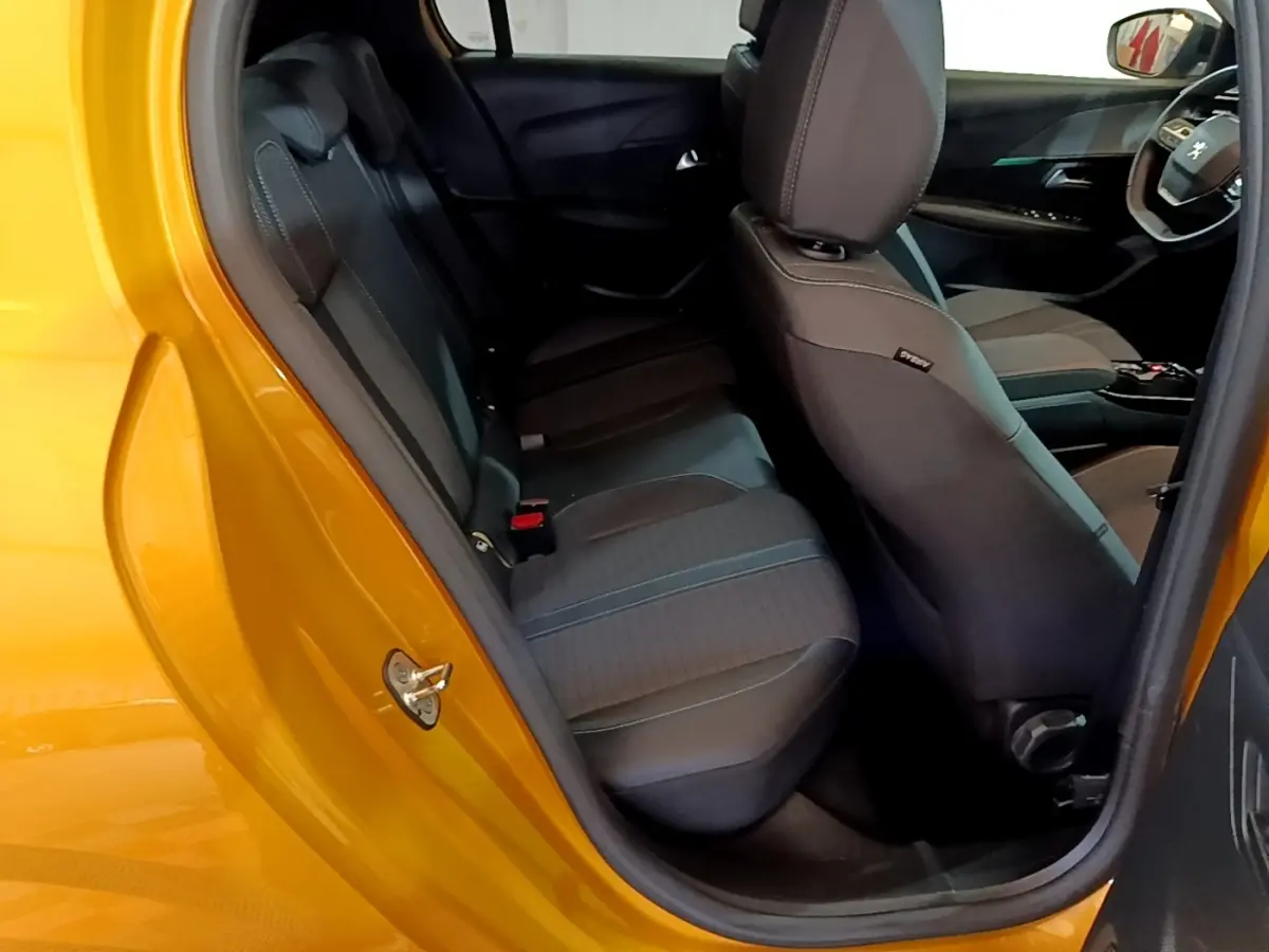 Vue intérieure côté arrière gauche d'une Peugeot 208 jaune 2023, montrant les sièges arrière et avant en tissu noir.