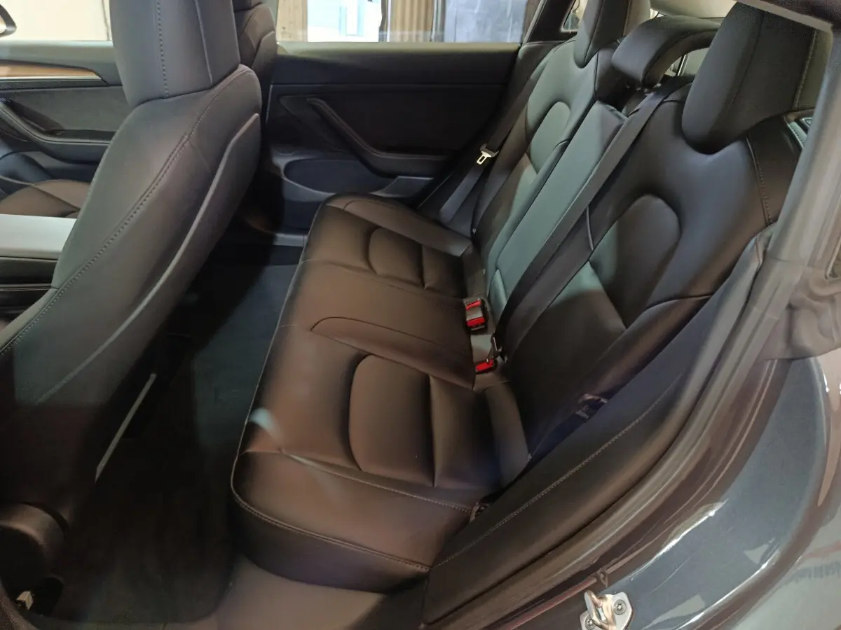 Vue intérieure côté droit sur la banquette arrière en cuir noir du Tesla Model 3 Grande Autonomie gris foncé 2022.