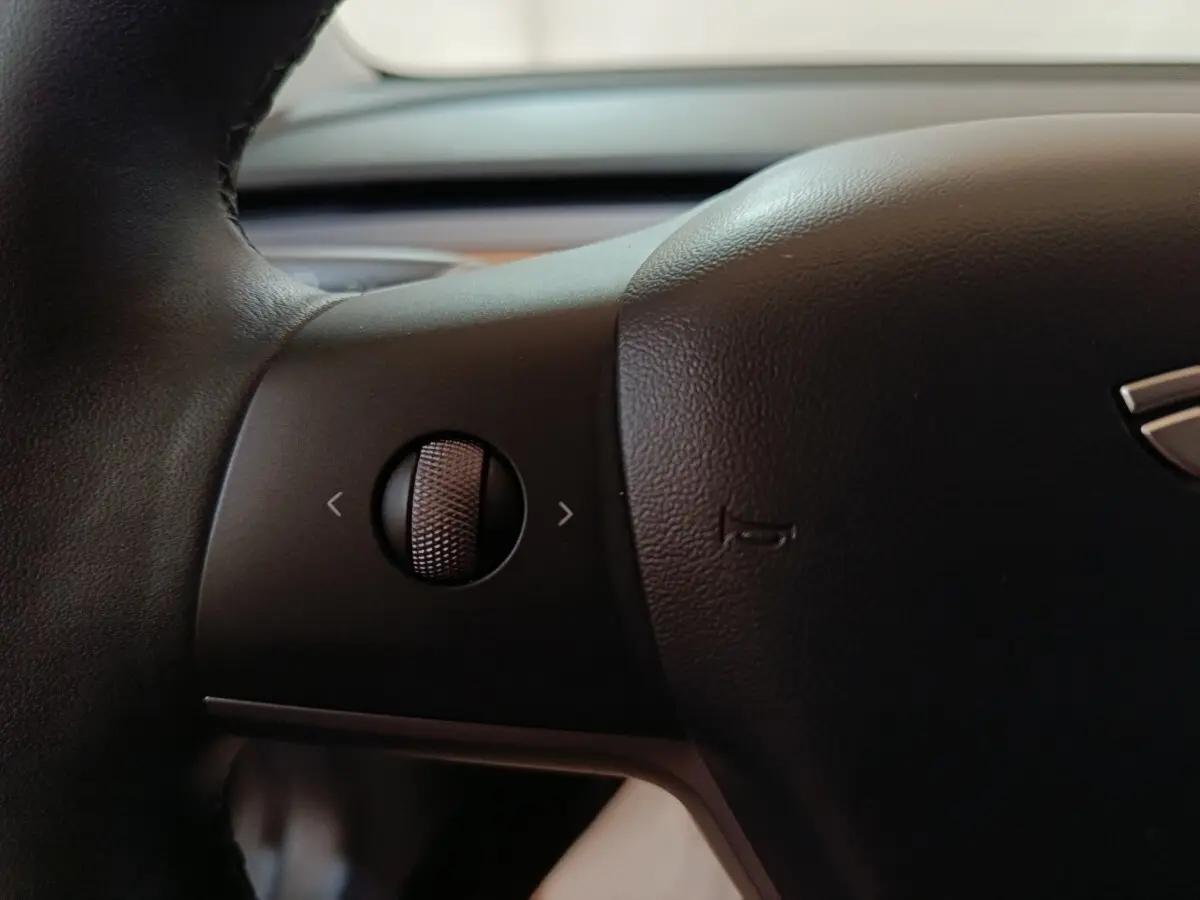Gros plan sur la molette de commande sur le volant noir d'une Tesla Model 3 Grande Autonomie 2022.