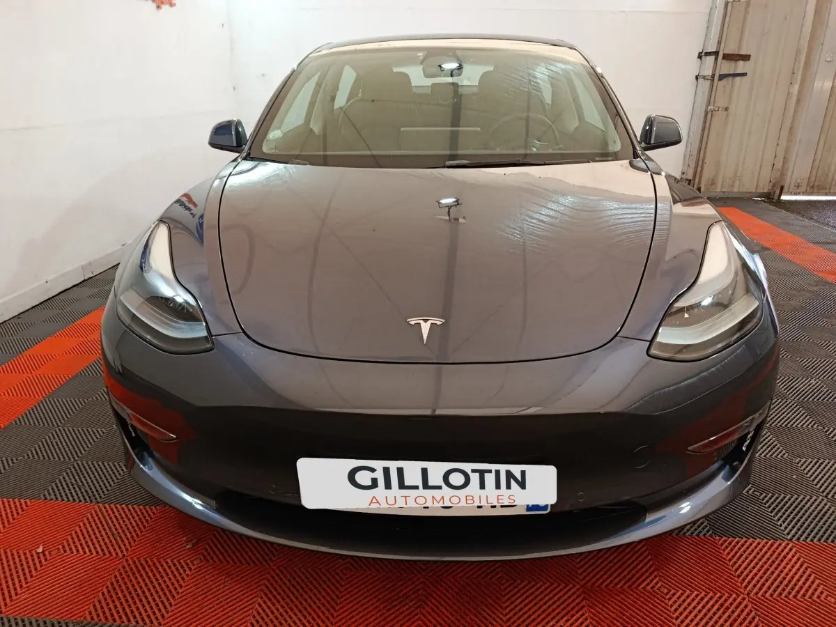 Vue avant d'une Tesla Model 3 gris foncé 2022, avec phares LED et logo Tesla visible sur le capot.