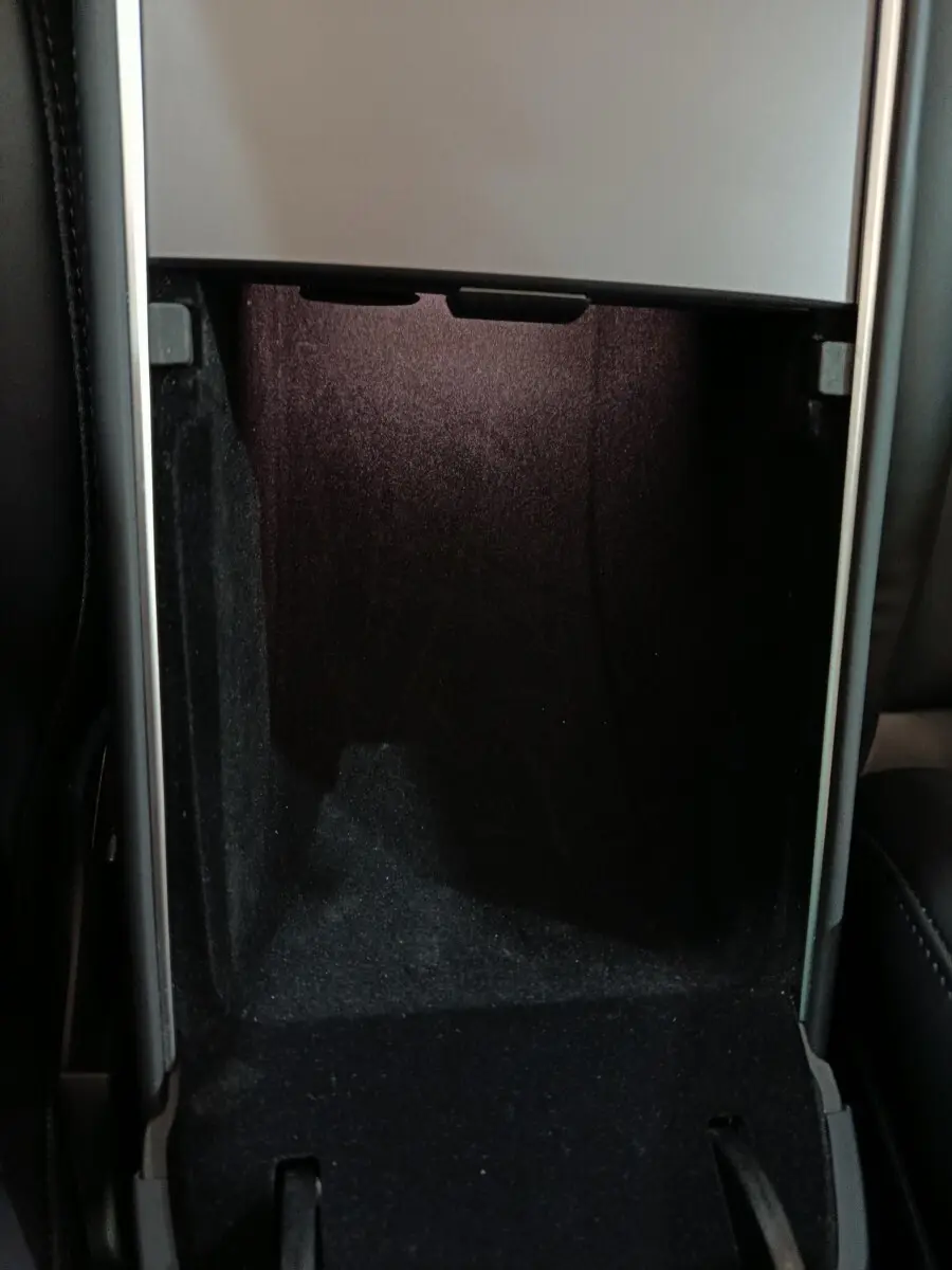 Intérieur du coffre central ouvert d'une Tesla Model 3 gris foncé, montrant un espace de rangement noir profond.