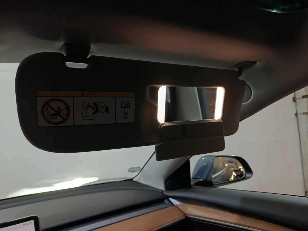 Détail du pare-soleil avec miroir éclairé côté conducteur dans l'habitacle d'une Tesla Model 3 gris foncé.
