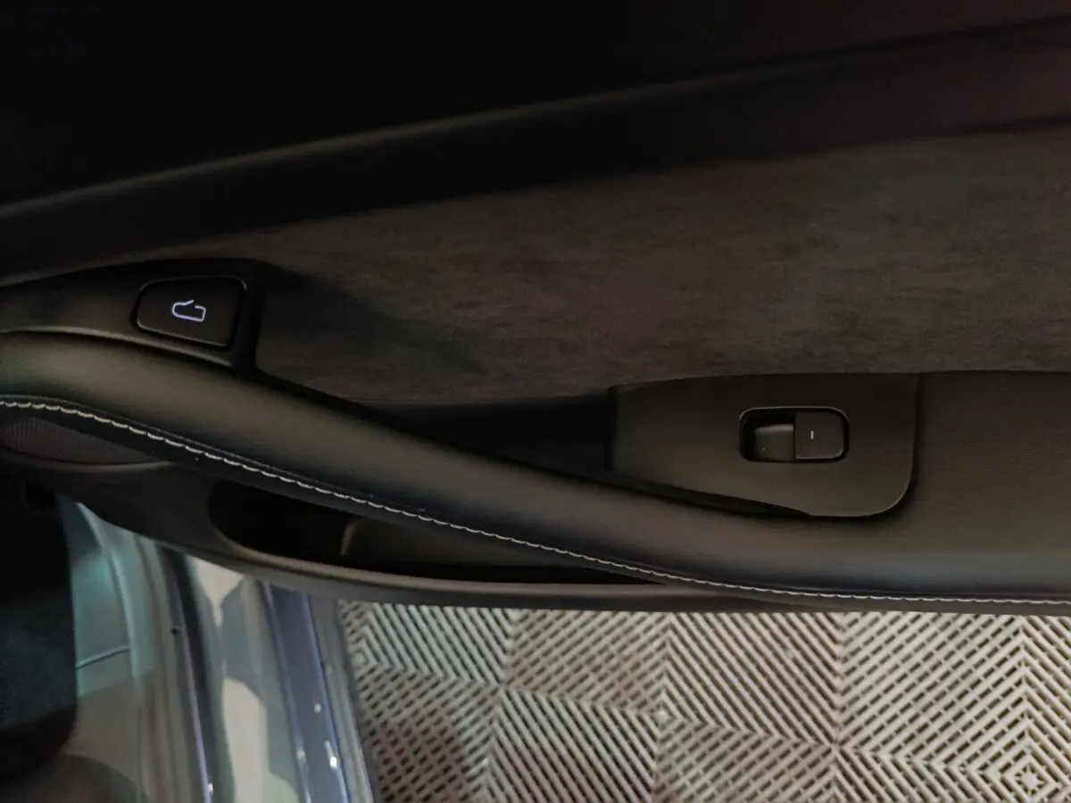 Gros plan sur la poignée intérieure côté gauche d’une Tesla Model 3 gris foncé avec bouton de verrouillage.