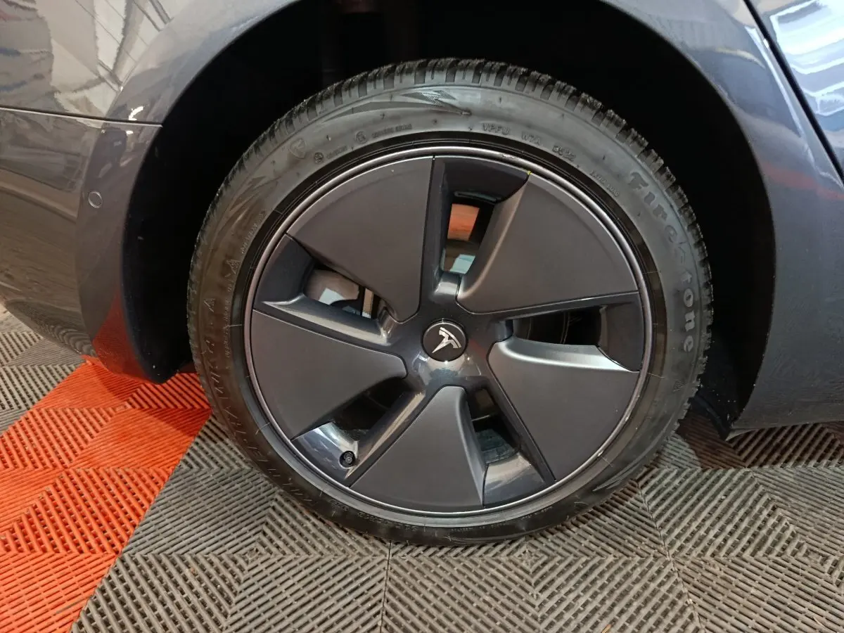 Vue rapprochée sur la roue arrière droite d'une Tesla Model 3 Grande Autonomie gris foncé de 2022.