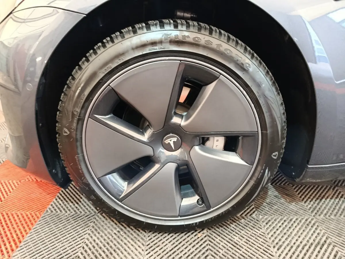 Gros plan sur la roue avant droite gris foncé d’une Tesla Model 3 Grande Autonomie 2022 avec jante aérodynamique.