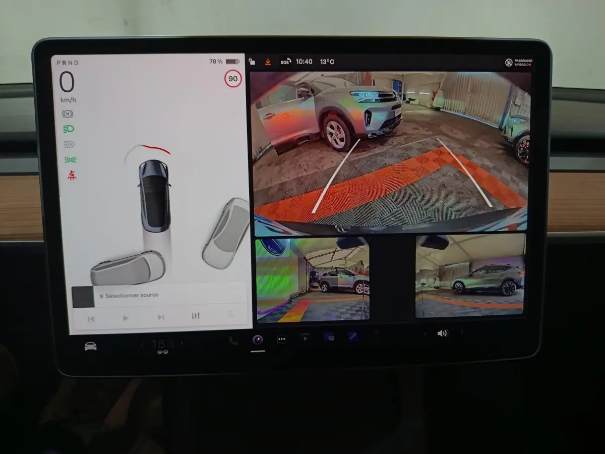 Écran central Tesla Model 3 2022 montrant caméra de recul et vues latérales d’un SUV gris en parking couvert.