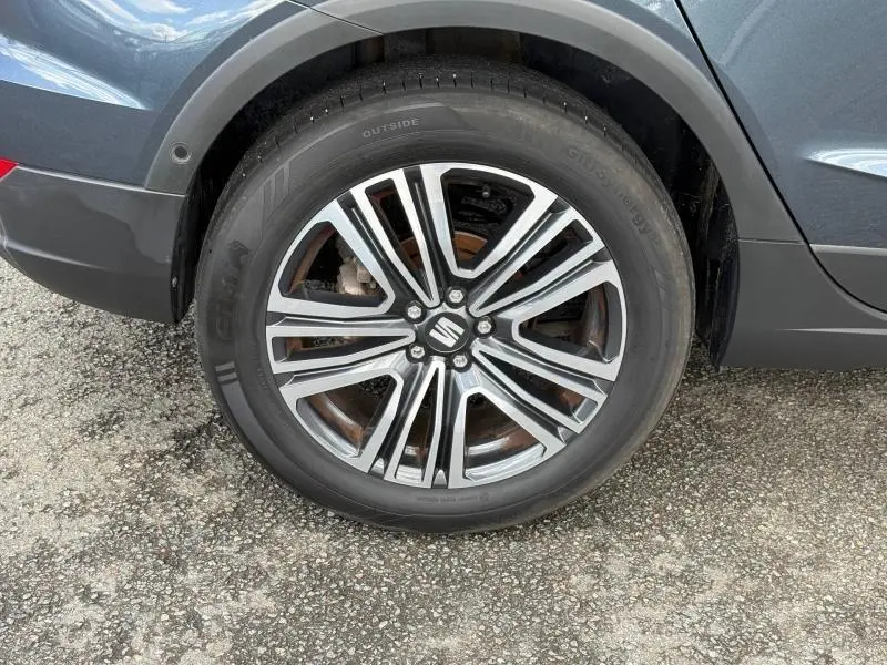 Gros plan sur la roue avant droite du SEAT Arona 2025 bleu saphir métal avec jante alliage multibranches et logo SEAT central.