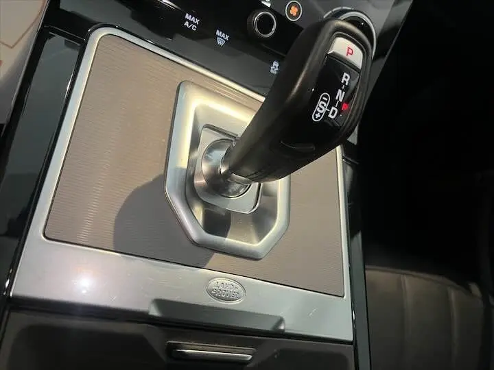 Le levier de vitesses automatique noir du Range Rover Evoque II 2.0 D180 SE vu en gros plan sur console argentée.